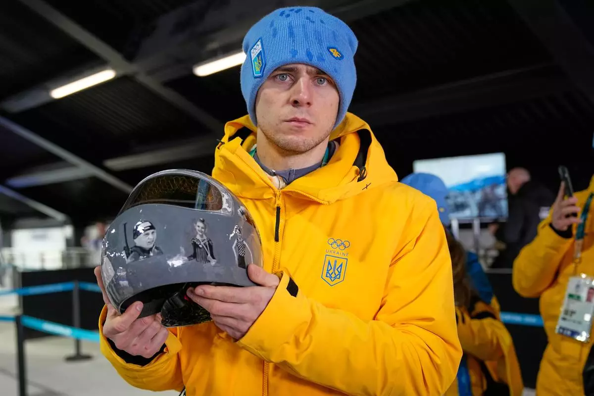 Ukrainian skeleton athlete Vladyslav Heraskevych holds his crash helmet as he stands in the mixed zone of the sliding center at the 2026 Winter Olympics, in Cortina d'Ampezzo, Italy, Thursday, Feb. 12, 2026. (AP Photo/Alessandra Tarantino)