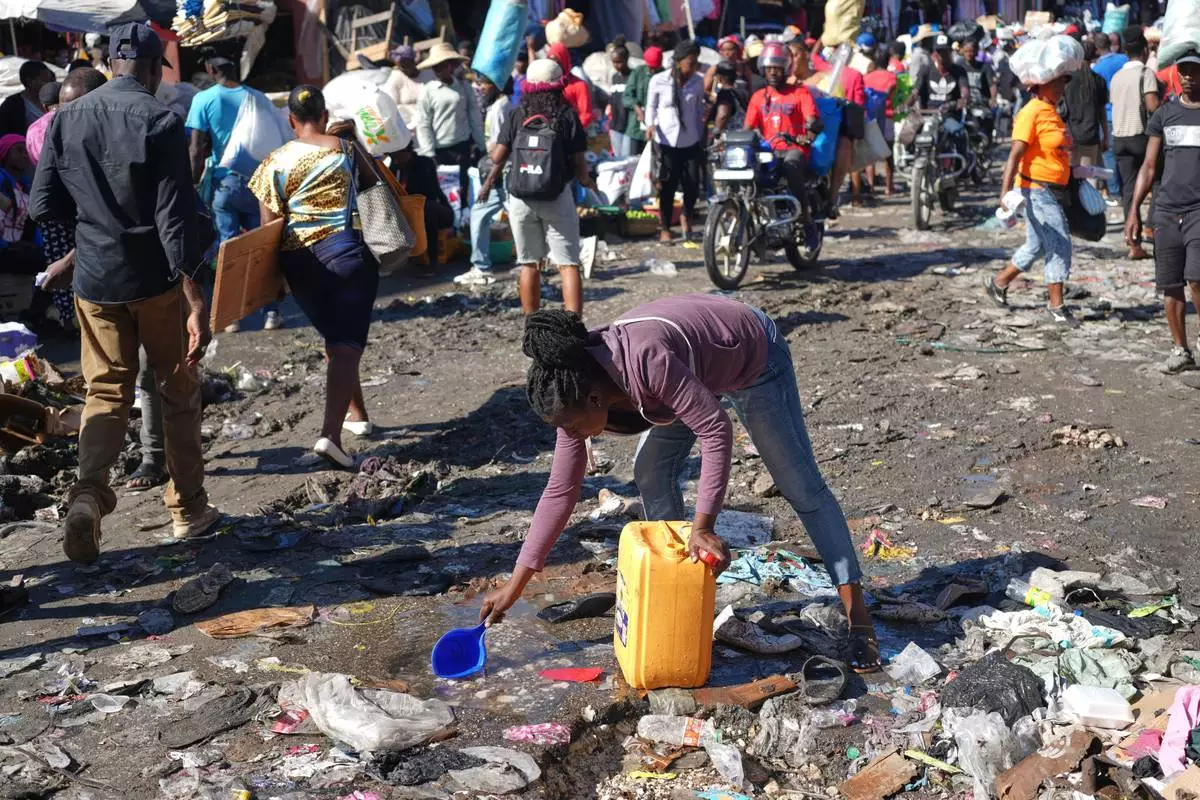 A woman collects water from a puddle in the Petion-Ville neighborhood of Port-au-Prince, Haiti, Wednesday, Feb. 11, 2026. (AP Photo/Odelyn Joseph)