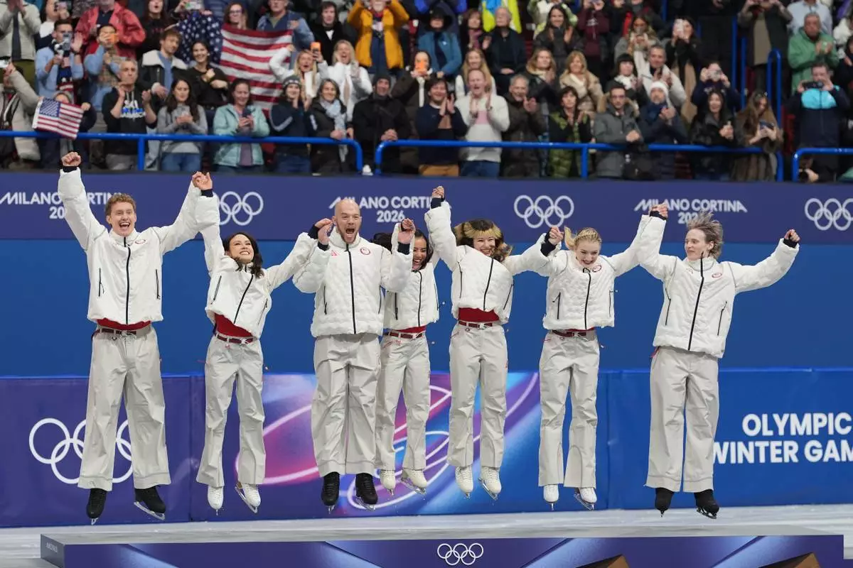 Team USA jump on the podium to receive their gold medals after the figure skating team event at the 2026 Winter Olympics, in Milan, Italy, Sunday, Feb. 8, 2026. (AP Photo/Stephanie Scarbrough)