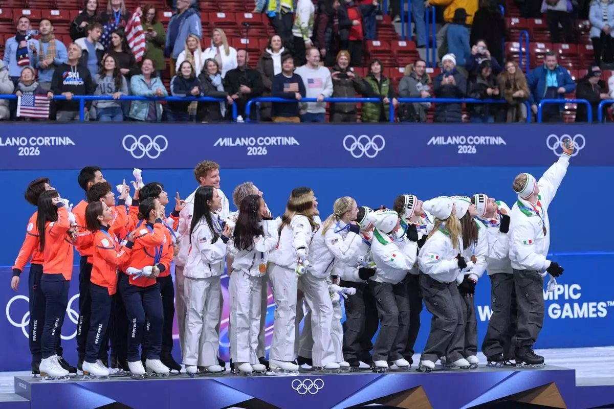 From left to right, silver medalists Team Japan, gold medalists Team USA and bronze medalists Team Italy take a big group selfie with their medals after the figure skating team event at the 2026 Winter Olympics, in Milan, Italy, Sunday, Feb. 8, 2026.(AP Photo/Stephanie Scarbrough)