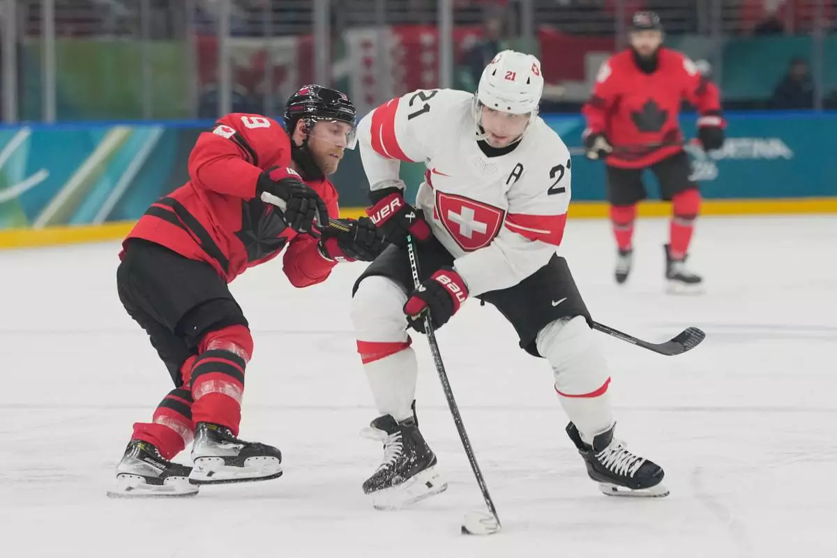 Canada's Sam Bennett, left, challenges Switzerland's Kevin Fiala during a preliminary round match of men's ice hockey between Canada and Switzerland at the 2026 Winter Olympics, in Milan, Italy, Friday, Feb. 13, 2026. (AP Photo/Hassan Ammar)