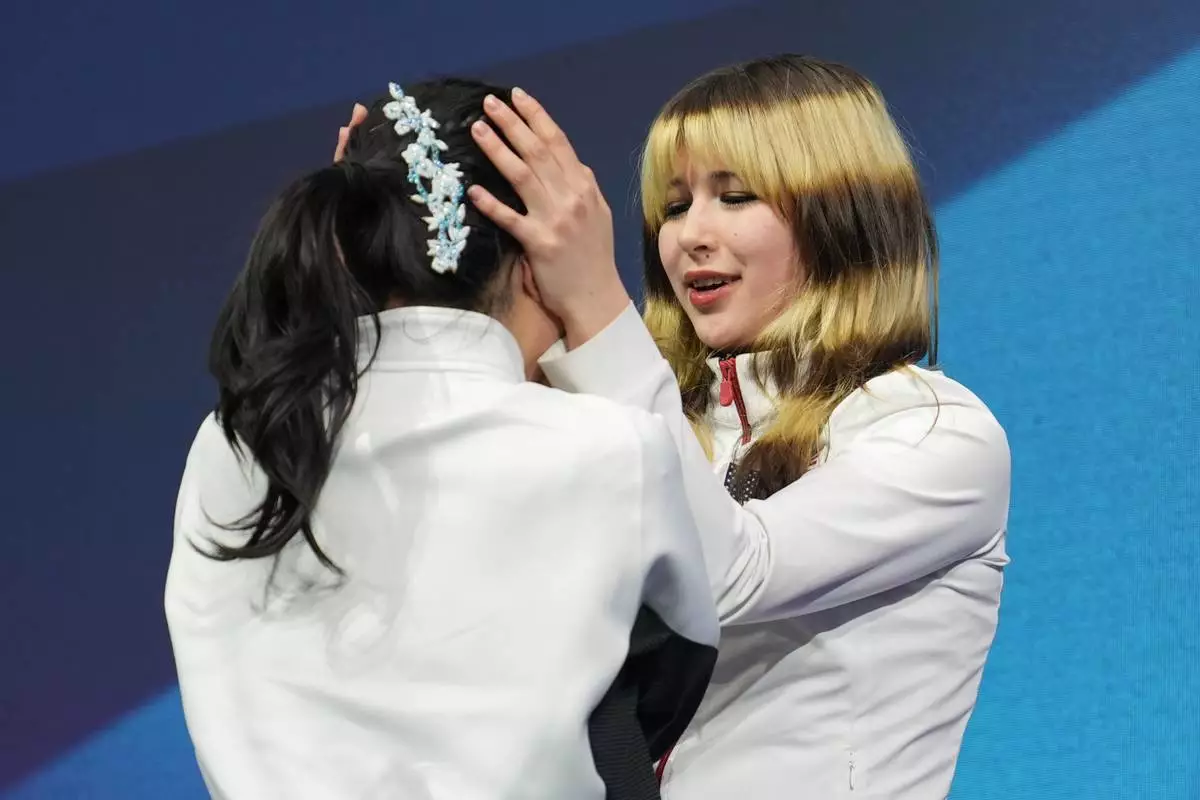 Gold medalist Alysa Liu of the United States hugs bronze medalist Ami Nakai of Japan after the women's figure skating free program at the 2026 Winter Olympics, in Milan, Italy, Thursday, Feb. 19, 2026. (AP Photo/Stephanie Scarbrough)