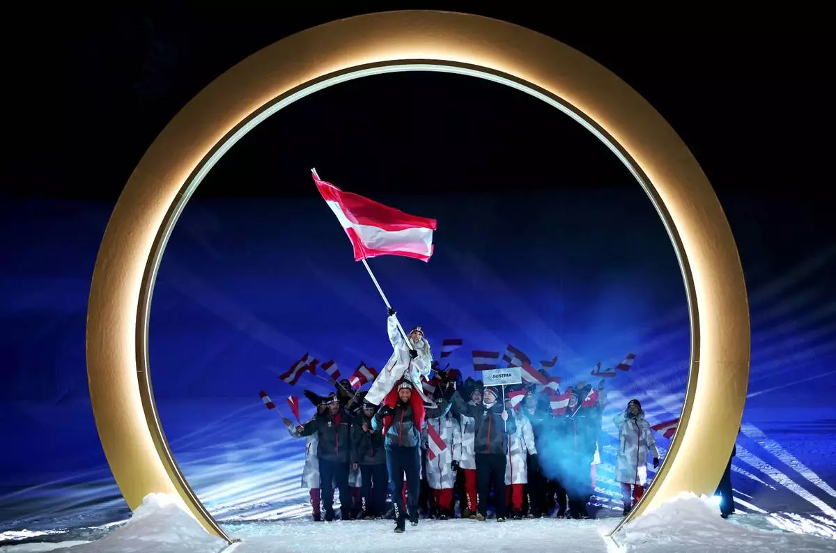 Austria's flag bearers, Anna Gasser and Benjamin Karl enter with the team, during the Olympic opening ceremony, at the 2026 Winter Olympics, in Livigno, Italy, Friday, Feb. 6, 2026. (Cameron Spencer, Pool Photo via AP)