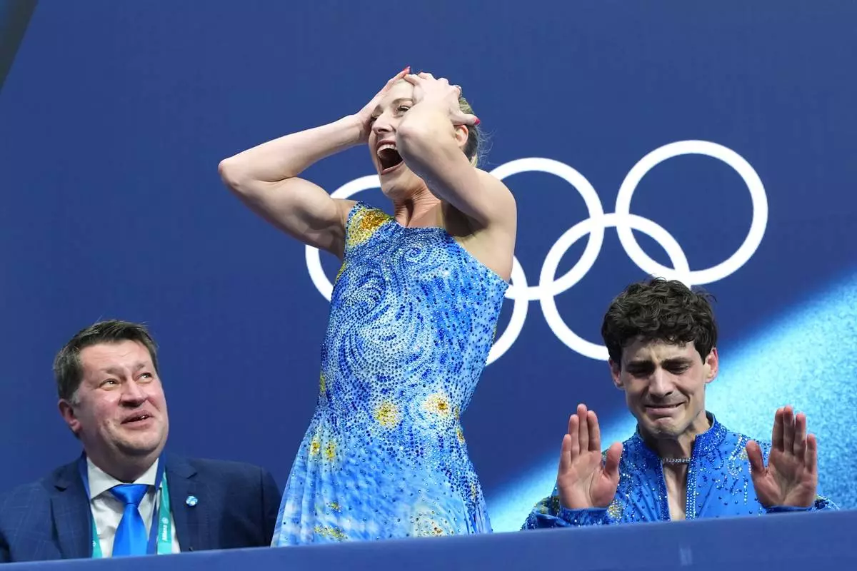 Piper Gilles, center, and Paul Poirier, right, of Canada react to their scores after competing during the ice dancing free skate in figure skating at the 2026 Winter Olympics, in Milan, Italy, Wednesday, Feb. 11, 2026. (AP Photo/Stephanie Scarbrough)