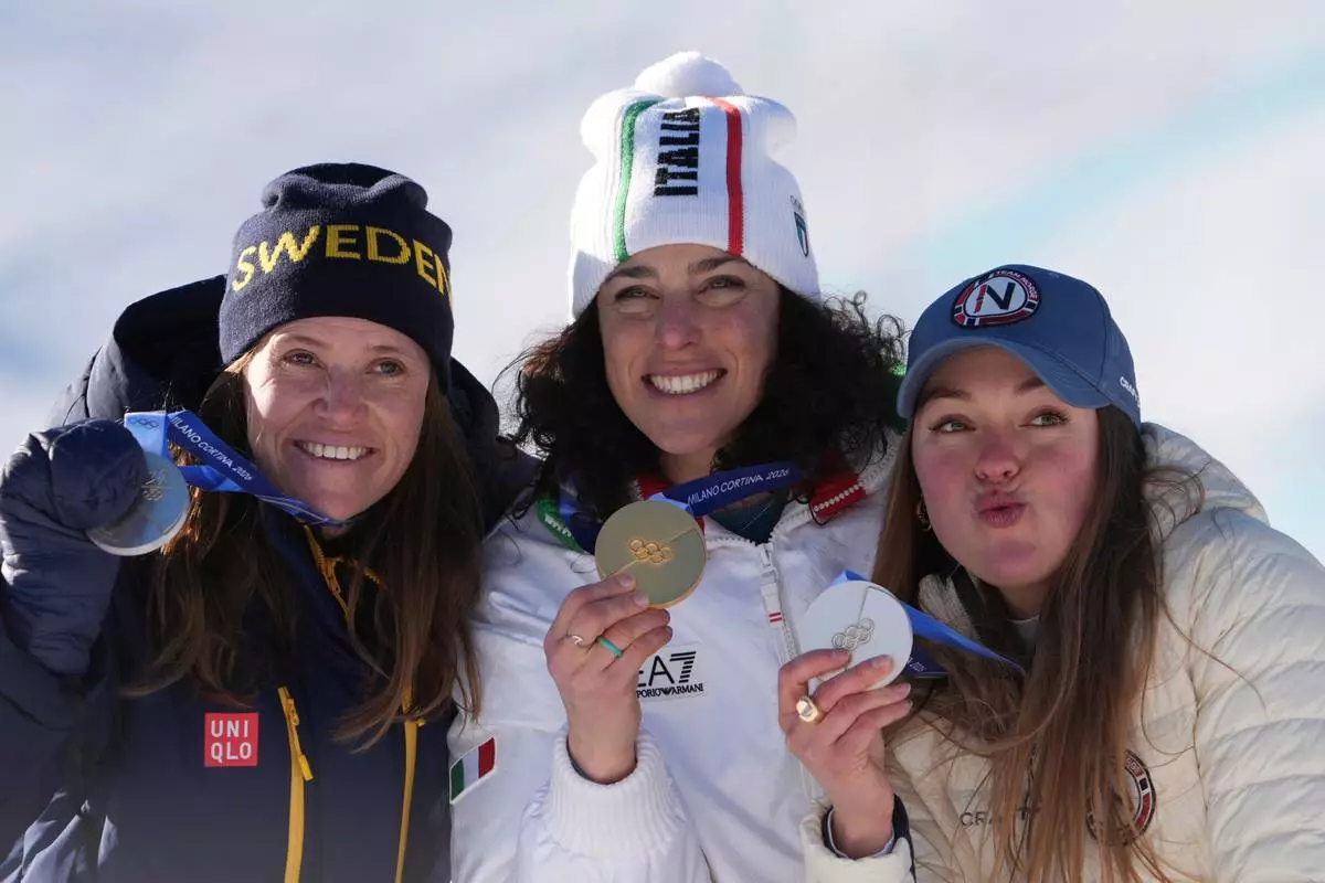 Italy's Federica Brignone, center, gold medalist in an alpine ski, women's giant slalom race, and joint silver medalists Sweden's Sara Hector, left, and Norway's Thea Louise Stjernesund, show their medals, at the 2026 Winter Olympics, in Cortina d'Ampezzo, Italy, Sunday, Feb. 15, 2026. (AP Photo/Jacquelyn Martin)