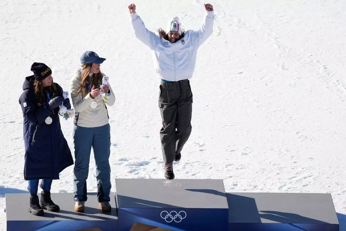 Italy's Federica Brignone, right, celebrates winning the gold medal in an alpine ski, women's giant slalom race, next to joint silver medalists Sweden's Sara Hector, left, and Norway's Thea Louise Stjernesund, at the 2026 Winter Olympics, in Cortina d'Ampezzo, Italy, Sunday, Feb. 15, 2026. (AP Photo/Andy Wong)