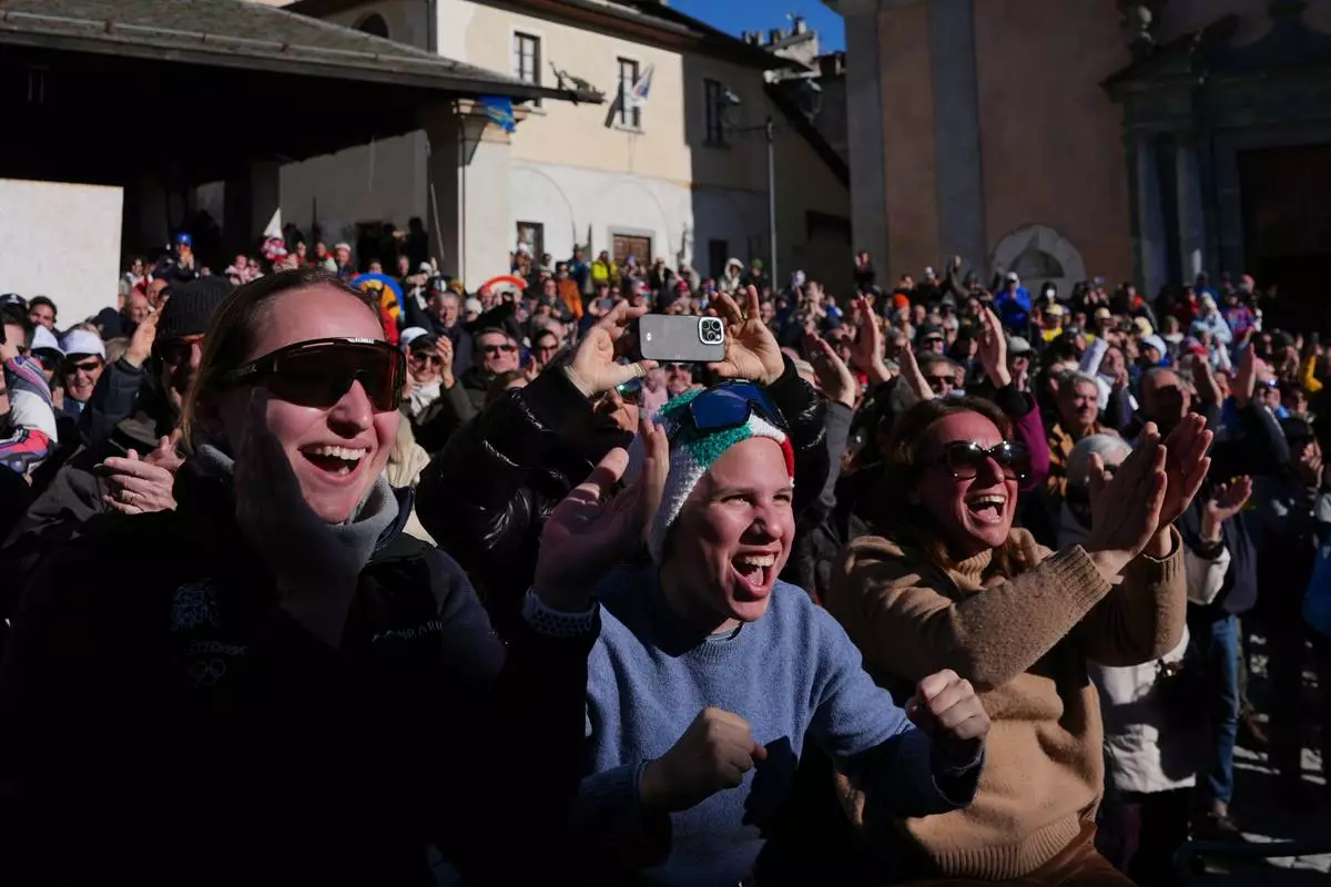 Fans react as they watch on a big screen in Piazza Cavour as Italy's Federica Brignone wins a gold medal in an alpine ski, women's giant slalom race, at the 2026 Winter Olympics, in Bormio, Italy, Sunday, Feb. 15, 2026. (AP Photo/Rebecca Blackwell)