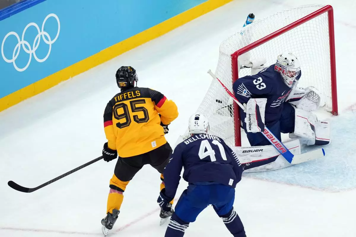 Germany's Frederik Tiffels (95) scores a goal against France goalkeeper Julian Junca (33) during the first period of a men's ice hockey qualification playoff game at the 2026 Winter Olympics, in Milan, Italy, Tuesday, Feb. 17, 2026. (AP Photo/Carolyn Kaster)