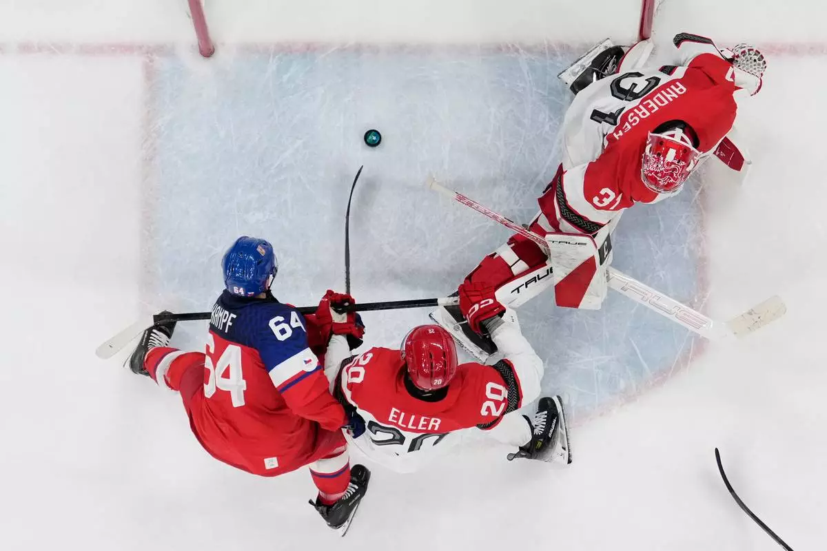 Czechia's David Kampf (64) scores a goal against Denmark's Lars Eller (20) and Denmark's goalkeeper Frederik Andersen (31) during a men's ice hockey qualification playoff game between Czechia and Denmark at the 2026 Winter Olympics, in Milan, Italy, Tuesday, Feb. 17, 2026. (AP Photo/Carolyn Kaster)