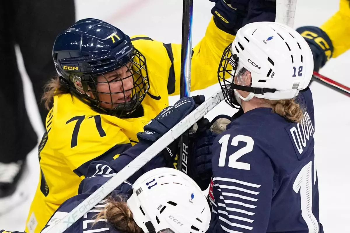 France's Estelle Duvin, right, fights with Sweden's Anna Kjellbin during a preliminary round match of women's ice hockey between France and Sweden at the 2026 Winter Olympics, in Milan, Italy, Sunday, Feb. 8, 2026. (AP Photo/Petr David Josek)