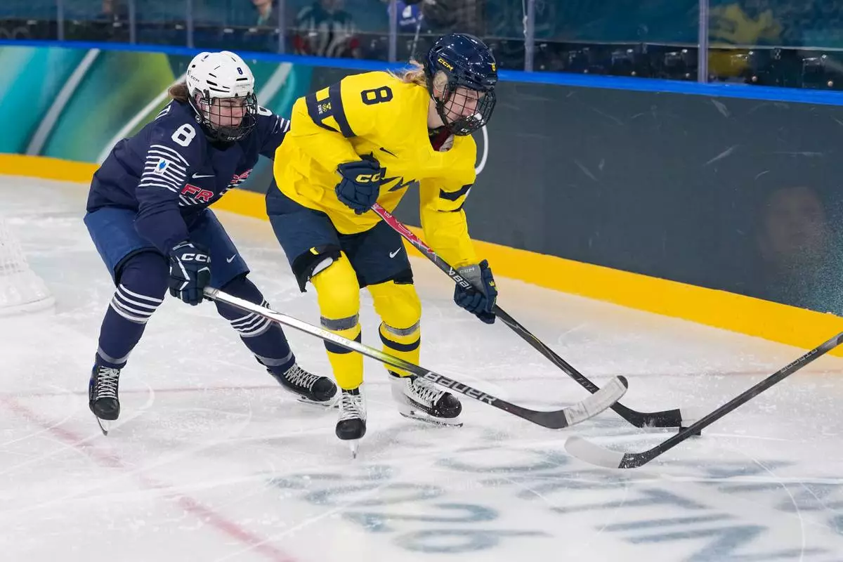 France's Jade Barbirati, left, challenges Sweden's Hilda Svensson during a preliminary round match of women's ice hockey between the France and Sweden at the 2026 Winter Olympics, in Milan, Italy, Sunday, Feb. 8, 2026. (AP Photo/Petr David Josek)
