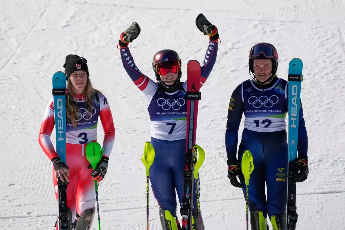 United States' Mikaela Shiffrin, center, winner of an alpine ski, women's slalom race, celebrates with second-placed Switzerland's Camille Rast, left, and third-placed Sweden's Anna Swenn Larsson, at the 2026 Winter Olympics, in Cortina d'Ampezzo, Italy, Wednesday, Feb. 18, 2026. (AP Photo/Andy Wong)