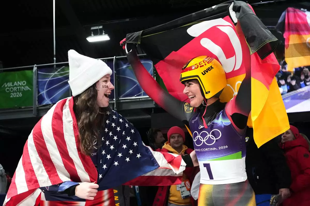 Germany's gold medalist Julia Taubitz, right, and United States' bronze medlist Ashley Farquharson, left, celebrate after the women's single luge competition at the 2026 Winter Olympics, in Cortina d'Ampezzo, Italy, Tuesday, Feb. 10, 2026. (AP Photo/Alessandra Tarantino)