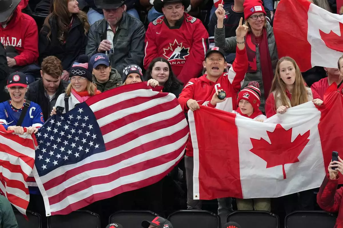 Fans cheer for their teams during the first period of the women's ice hockey gold medal game between the United States and Canada at the 2026 Winter Olympics, in Milan, Italy, Thursday, Feb. 19, 2026. (AP Photo/Carolyn Kaster)