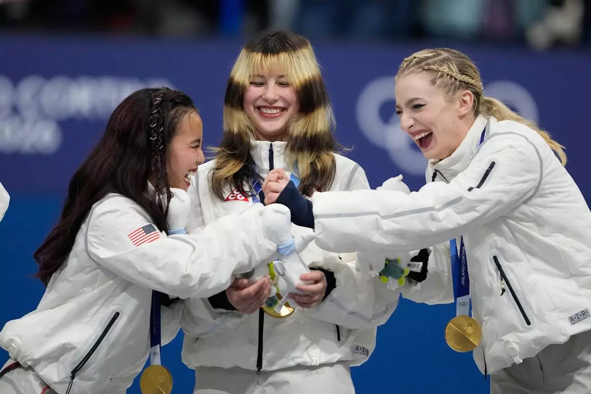 From left, Ellie Kam, Alysa Liu, and Amber Glenn of Team USA react after receiving their gold medals for the figure skating team event at the 2026 Winter Olympics, in Milan, Italy, Sunday, Feb. 8, 2026. (AP Photo/Ashley Landis)