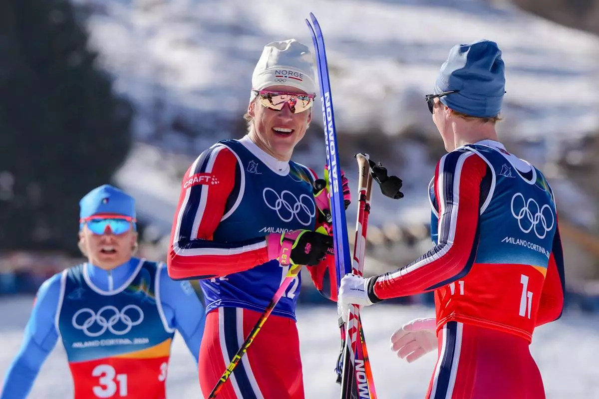 Johannes Hoesflot Klaebo, of Norway, center, speaks with teammate Einar Hedegart after winning the gold medal in the cross-country skiing men's team sprint free at the 2026 Winter Olympics, in Tesero, Italy, Wednesday, Feb. 18, 2026. (AP Photo/Kirsty Wigglesworth)