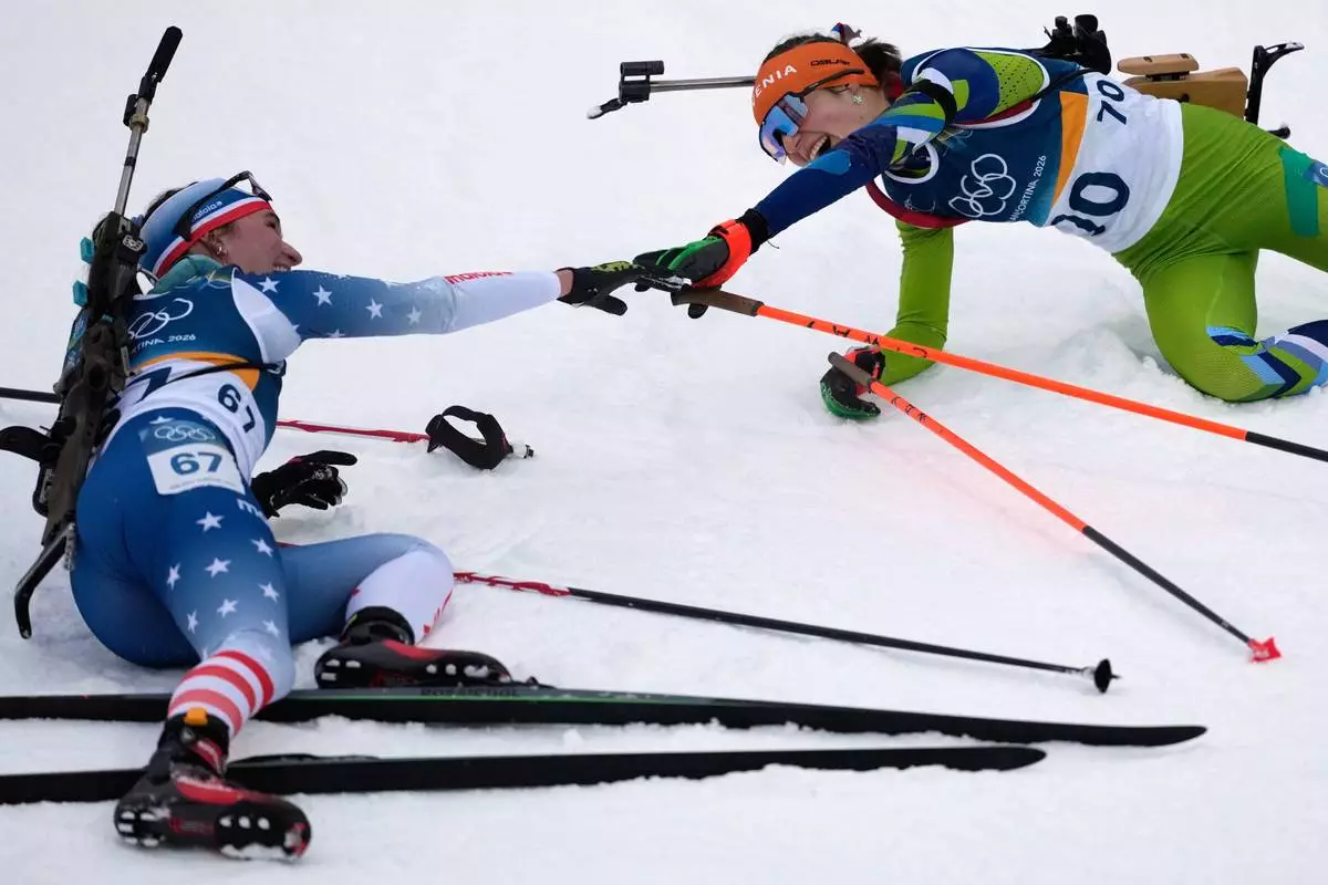 Lucinda Anderson, of the United States, left, reaches out to Lena Repinc, of Slovenia, after the women's 7.5-kilometer sprint biathlon race at the 2026 Winter Olympics in Anterselva, Italy, Saturday, Feb. 14, 2026. (AP Photo/Mosa'ab Elshamy)