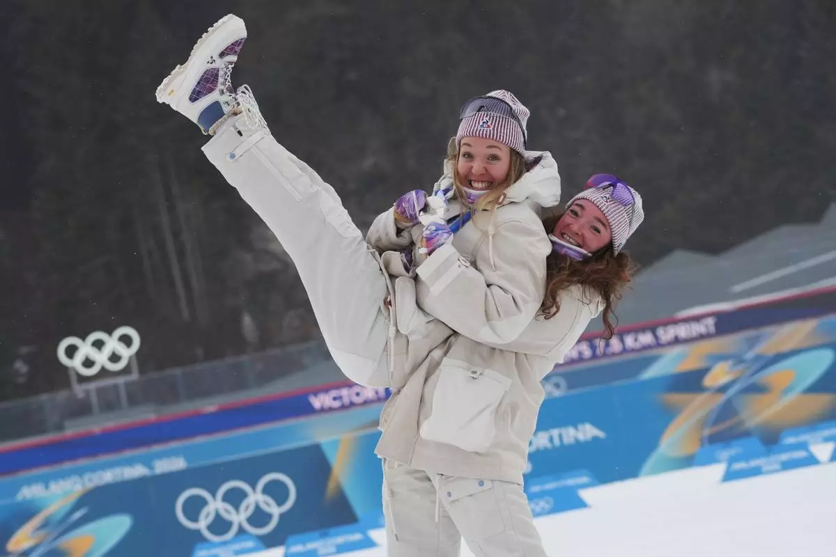 Bronze medalist Lou Jeanmonnot, of France, lifts silver medalist Oceane Michelon, of France, after the women's 7.5-kilometer sprint biathlon race at the 2026 Winter Olympics in Anterselva, Italy, Saturday, Feb. 14, 2026. (AP Photo/Andrew Medichini)