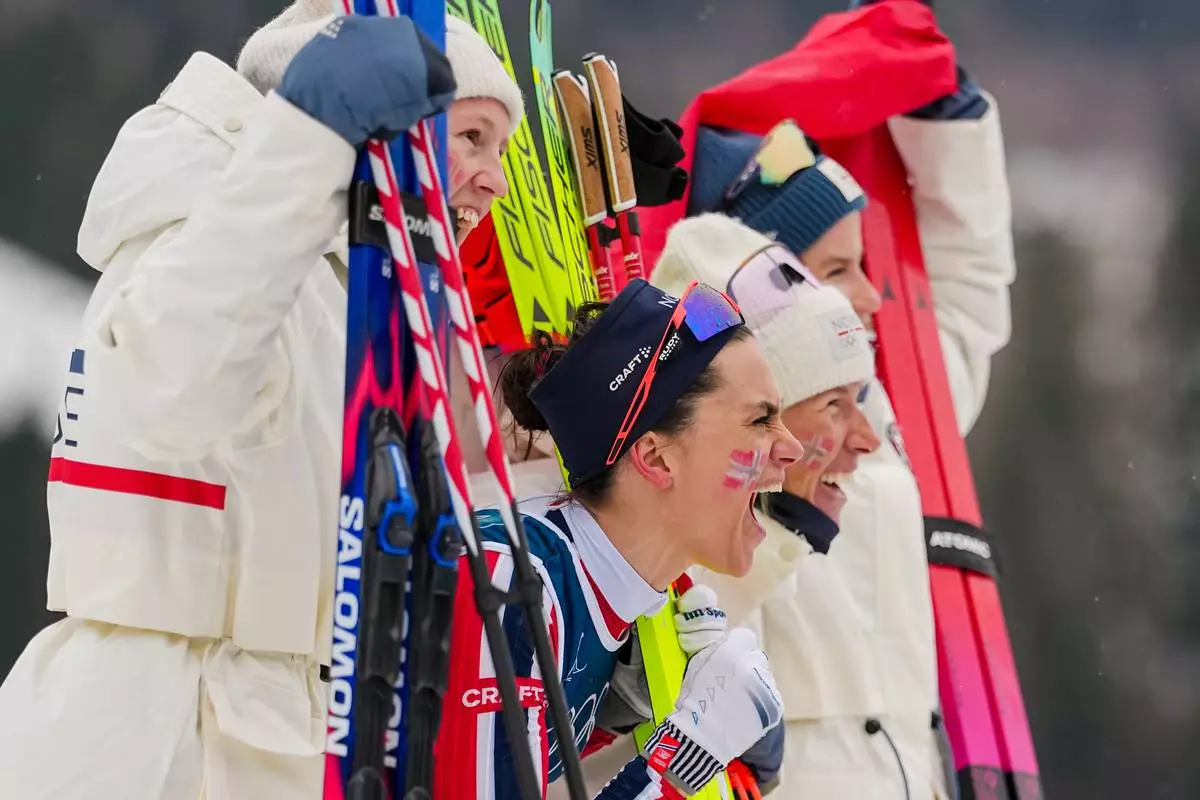 Heidi Weng, of Norway, center, and her teammates celebrate after winning the gold medal in the cross country skiing women's 4 x 7.5km relay at the 2026 Winter Olympics, in Tesero, Italy, Saturday, Feb. 14, 2026. (AP Photo/Matthias Schrader)