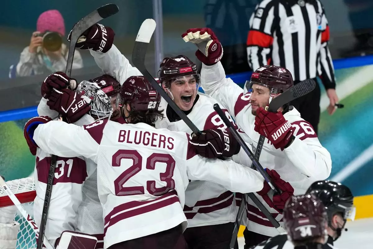 Latvia goalkeeper Arturs Silovs (31) celebrates with Teodors Blugers (23), Kristians Rubins (94) and Uvis Balinskis (26) after defeating Germany 4-3 in a men's ice hockey preliminary round match at the 2026 Winter Olympics, in Milan, Italy, Saturday, Feb. 14, 2026. (AP Photo/Carolyn Kaster)