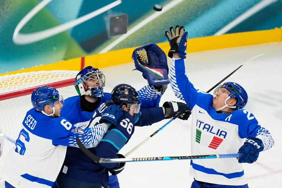 Italy's goalkeeper Damian Clara, center, and Italy's Diego Kostner, right, reach for the puck during a preliminary round match of men's ice hockey between Finland and Italy at the 2026 Winter Olympics, in Milan, Italy, Saturday, Feb. 14, 2026. (AP Photo/Hassan Ammar)