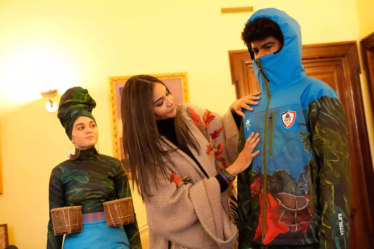 Italian-Haitian designer Stella Jean, center, helps Megan Thomas, right, and Livia Audain at the Haitian Embassy in Rome, Saturday, Jan. 31, 2026, wear the official uniform of the Haitian national team participating in the 2026 Winter Olympics. (AP Photo/Gregorio Borgia)