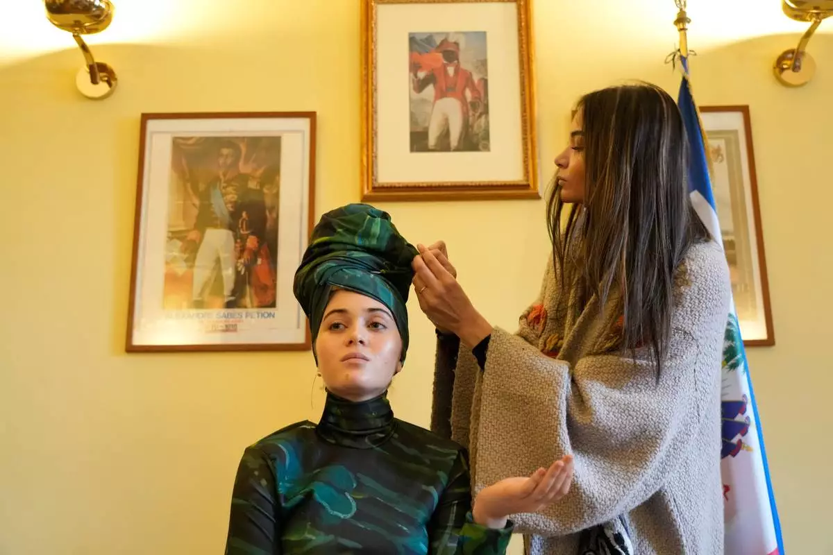 Italian-Haitian designer Stella Jean, right, helps Livia Audain at the Haitian Embassy in Rome, Saturday, Jan. 31, 2026, wear the official uniform of the Haitian national team participating in the 2026 Winter Olympics. (AP Photo/Gregorio Borgia)