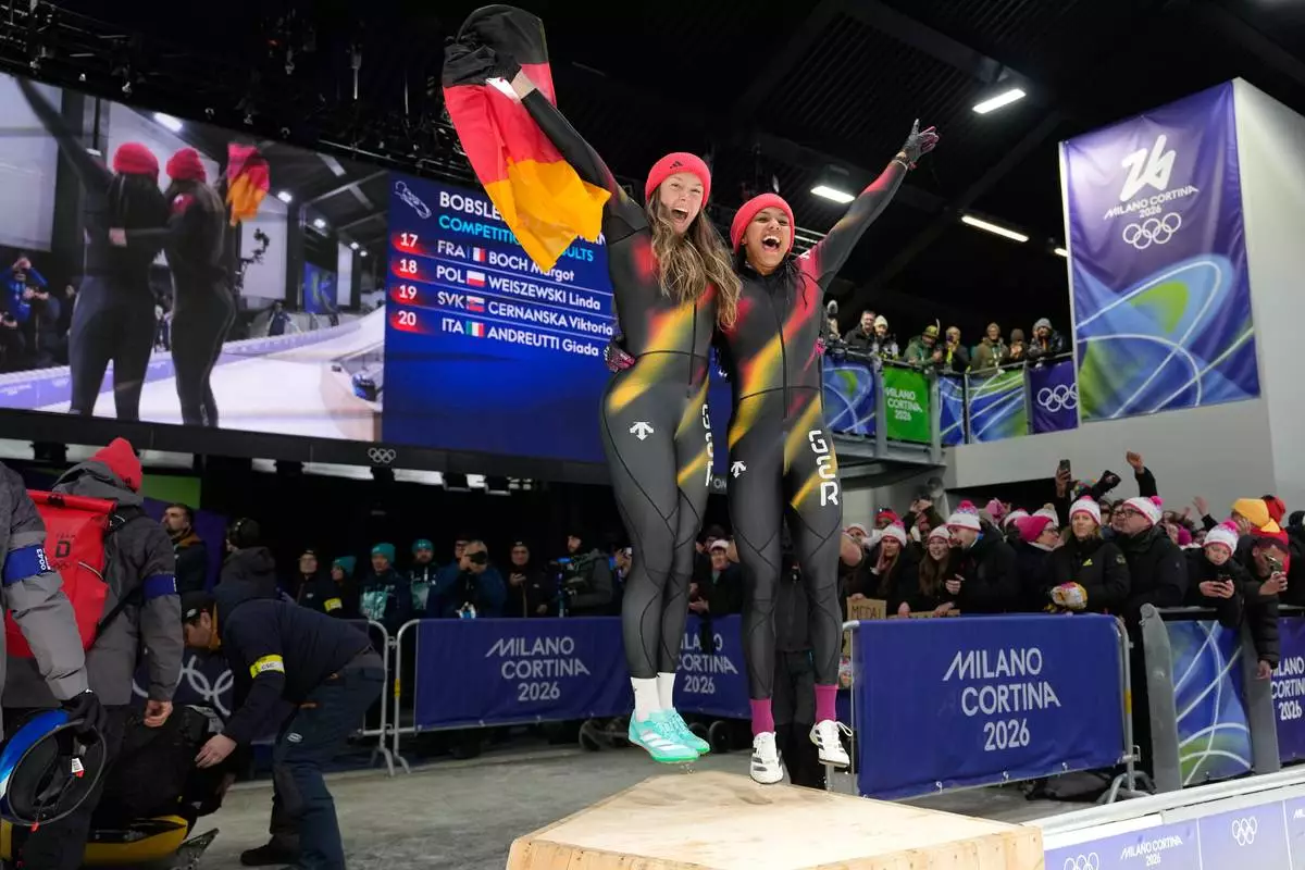 Germany's gold medalists Laura Nolte, left, and Deborah Levi celebrate after the two women bobsled competition at the 2026 Winter Olympics, in Cortina d'Ampezzo, Italy, Saturday, Feb. 21, 2026. (AP Photo/Alessandra Tarantino)