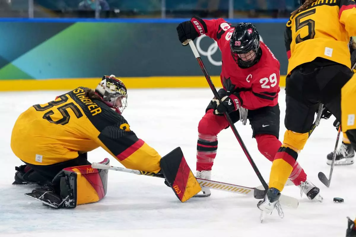 Canada's Marie-Philip Poulin (29) tries to control the puck in front of Germany goalkeeper Sandra Abstreiter (35) during the second period of a women's ice hockey quarterfinal match at the 2026 Winter Olympics, in Milan, Italy, Saturday, Feb. 14, 2026. (AP Photo/Carolyn Kaster)