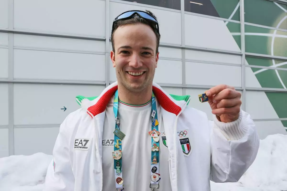 Italian luge athlete Leon Felderer poses for a photo with Italy's national pin, at the Cortina Olympic Village, during the 2026 Winter Olympics, in Cortina d'Ampezzo, Italy, Thursday Feb. 5, 2026. (AP Photo/Jennifer McDermott)