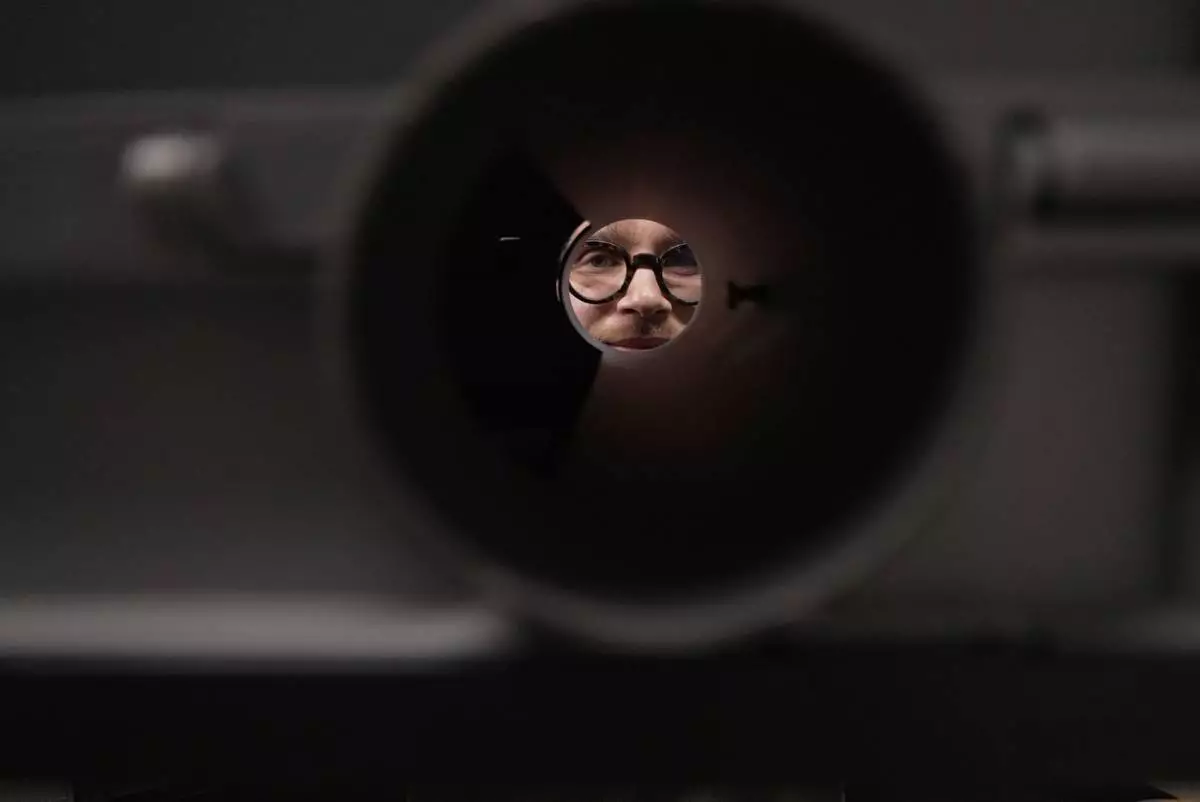 Doctoral student Marco Granata peers through a tunnel in a box that stoats can enter and exit freely, while a camera films them, Wednesday, Feb. 11, 2026, in Turin, Italy. (AP Photo/Brittany Peterson)