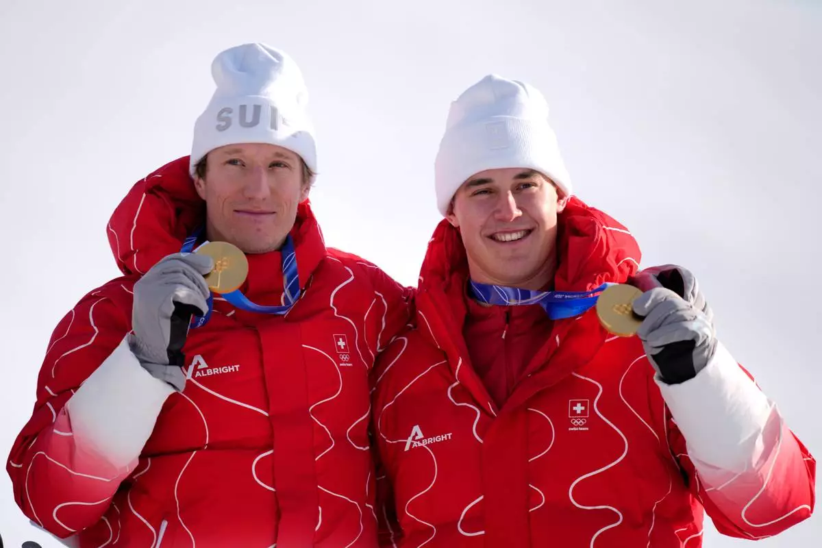Switzerland's Franjo von Allmen, right, and teammate Switzerland's Tanguy Nef show their gold medals in an alpine ski men's team combined race, at the 2026 Winter Olympics, in Bormio, Italy, Monday, Feb. 9, 2026. (AP Photo/Julia Demaree Nikhinson)