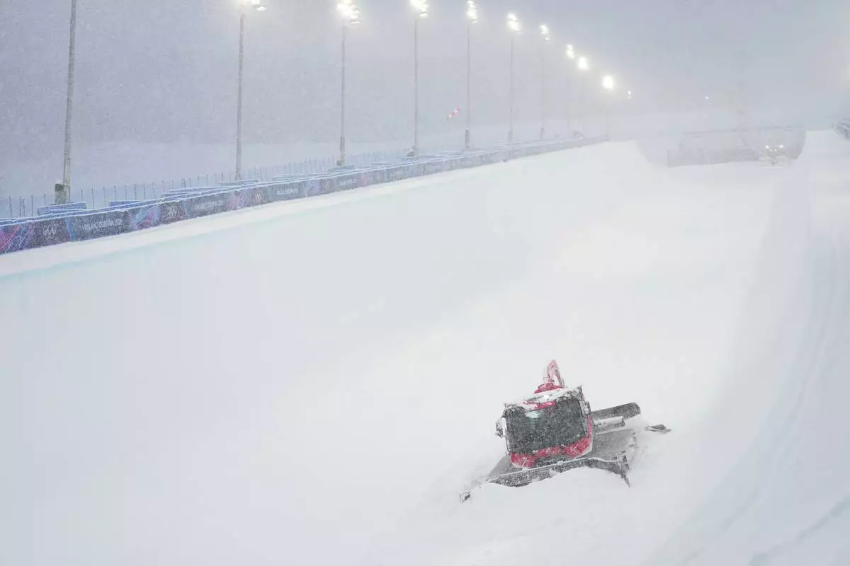 A worker clears snow from the course before the women's freestyle skiing halfpipe final at the 2026 Winter Olympics, in Livigno, Italy, Saturday, Feb. 21, 2026. (AP Photo/Lindsey Wasson)
