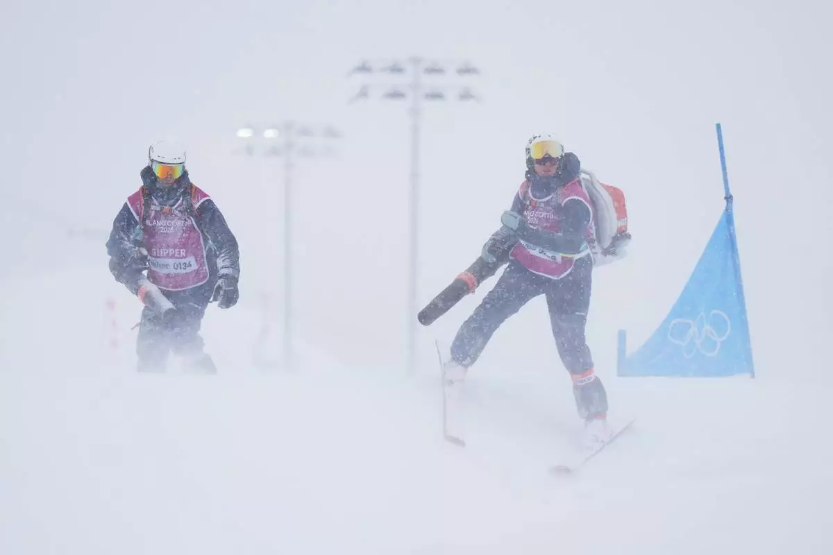 Workers blow snow off the course during the men's ski cross final at the 2026 Winter Olympics, in Livigno, Italy, Saturday, Feb. 21, 2026. (AP Photo/Abbie Parr)