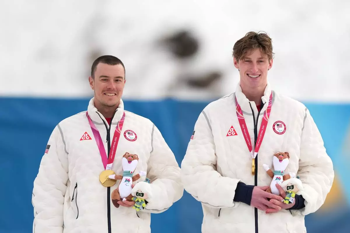 Jake Adicoff, of the United States, and his guide Reid Goble, pose on the podium after winning the gold medal in the cross country skiing men's 10Km interval start classic vision impaired final at the 2026 Winter Paralympics, in Tesero, Italy, Wednesday, March 11, 2026. (AP Photo/Evgeniy Maloletka)