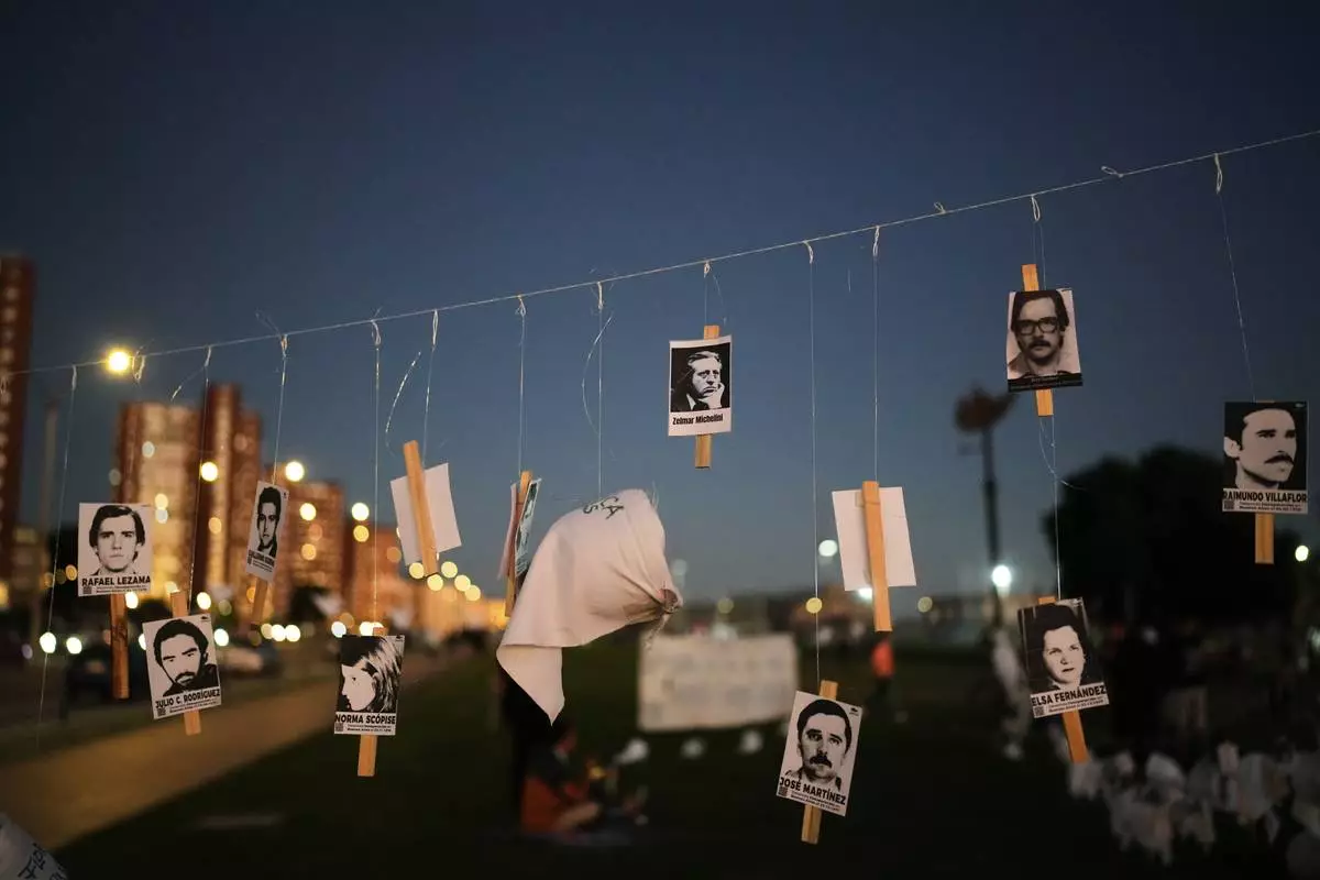 Photos of Uruguayans who disappeared in Argentina during Argentina's military dictatorship (1976–1983) are hung on a street in Montevideo, Uruguay, on the anniversary of the coup that brought the regime to power, Tuesday, March 24, 2026. (AP Photo/Matilde Campodonico)