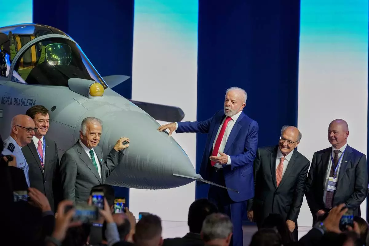 Brazilian President Luiz Inacio Lula da Silva, center, stands next to an F-39E Gripen fighter jet during a ceremony presenting the first supersonic aircraft assembled in Brazil, developed by Saab, at the Embraer plant in Gaviao Peixoto, Brazil, Wednesday, March 25, 2026. From left are Brazilian Air Force Commander Marcelo Kanitz Damasceno, Embraer CEO Francisco Gomes Neto, Defense Minister Jose Mucio, Lula, Vice President Geraldo Alckmin, and Saab CEO Micael Johansson. (AP Photo/Andre Penner)