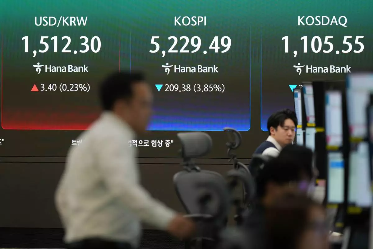 A dealer walks near the screens showing the Korea Composite Stock Price Index (KOSPI), the foreign exchange rate between U.S. dollar and South Korean won and the Korean Securities Dealers Automated Quotations (KOSDAQ) at a dealing room of Hana Bank in Seoul, South Korea, Monday, March 30, 2026. (AP Photo/Lee Jin-man)
