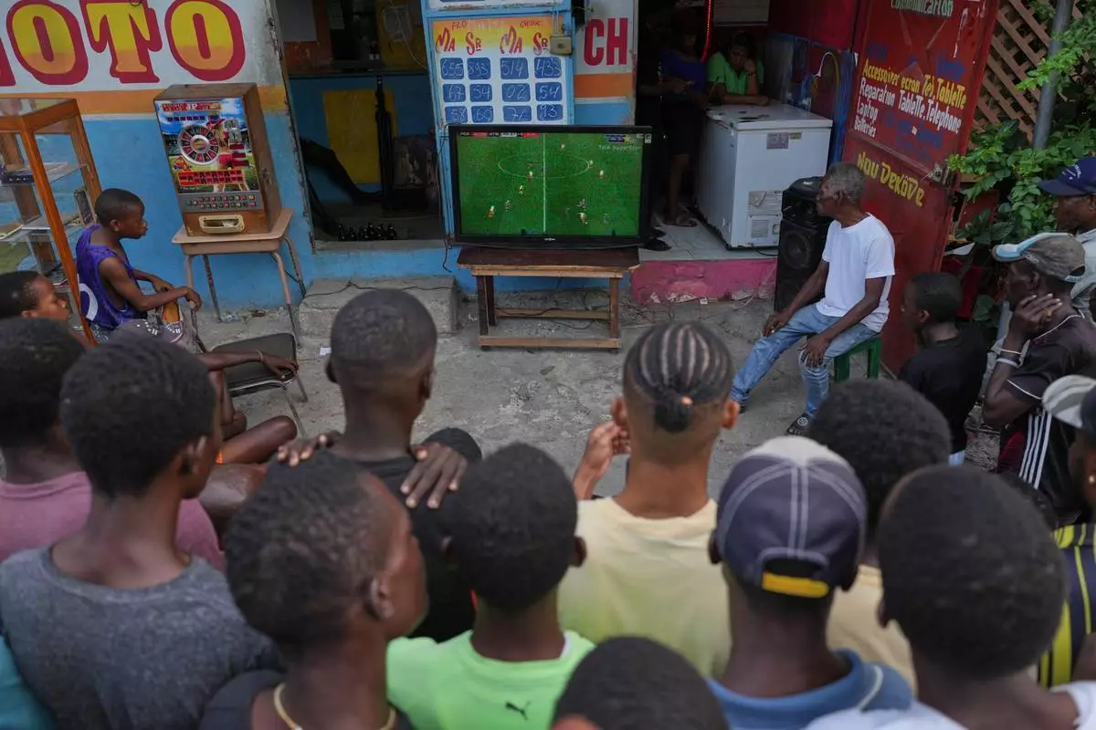 FILE - People watch a soccer match between FC Barcelona and Atlético Madrid on a sidewalk in downtown Port-au-Prince, Haiti, March 3, 2026. (AP Photo/Odelyn Joseph, File)