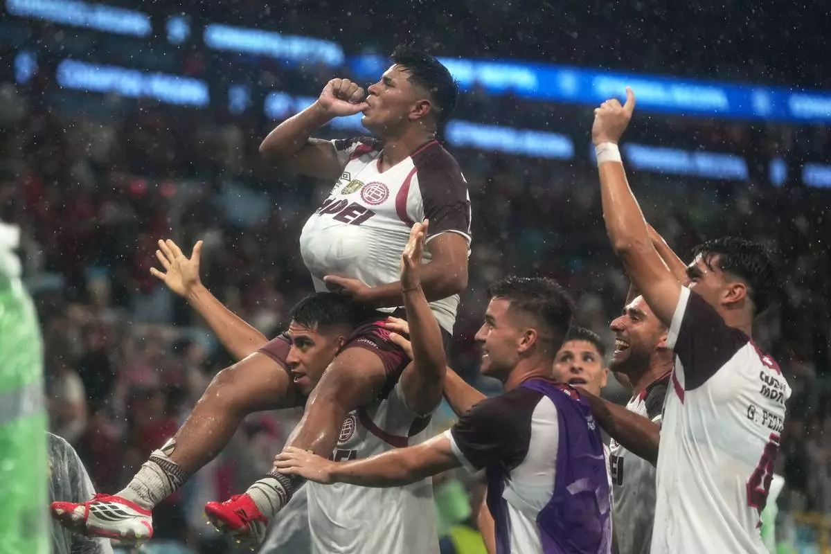 FILE - Dylan Aquino of Argentina's Lanus, top, celebrates with teammates after scoring his side's third goal during extra time in the Recopa Sudamericana second leg final soccer match against Brazil's Flamengo in Rio de Janeiro, Feb. 26, 2026. (AP Photo/Silvia Izquierdo, File)