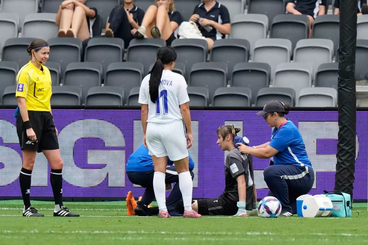 Uzbekistan's goalkeeper Maftuna Jonimqulova receives treatment from a trainer during the Women's Asia Cup soccer match between North Korea and Uzbekistan in Sydney, Tuesday, March 3, 2026. (AP Photo/Rick Rycroft)
