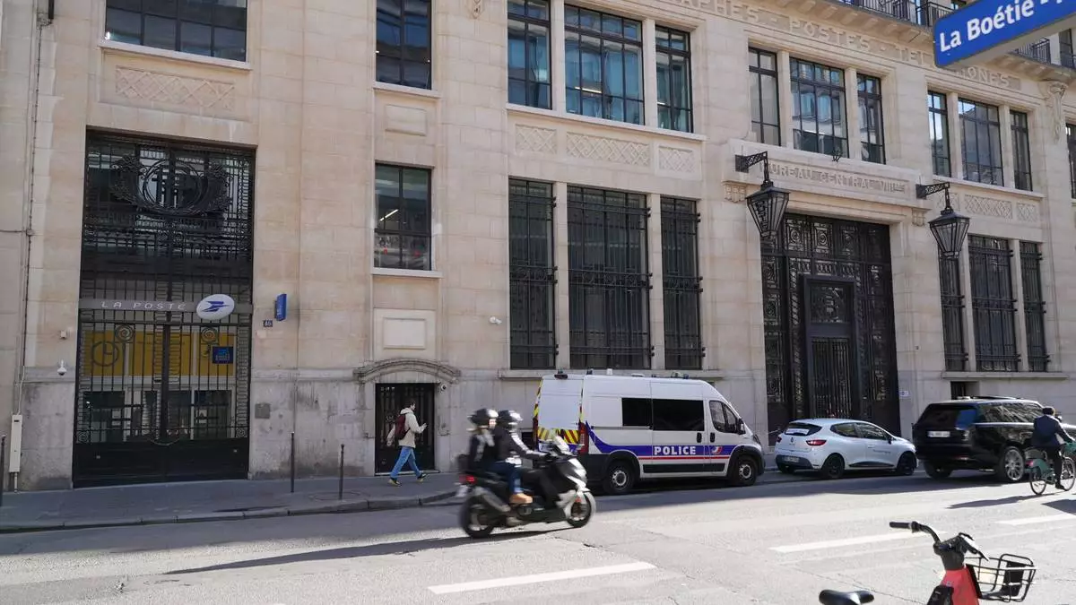 Police stand outside the Bank of America building in Paris, Saturday, March 28, 2026. (AP Photo/Nicolas Garriga)