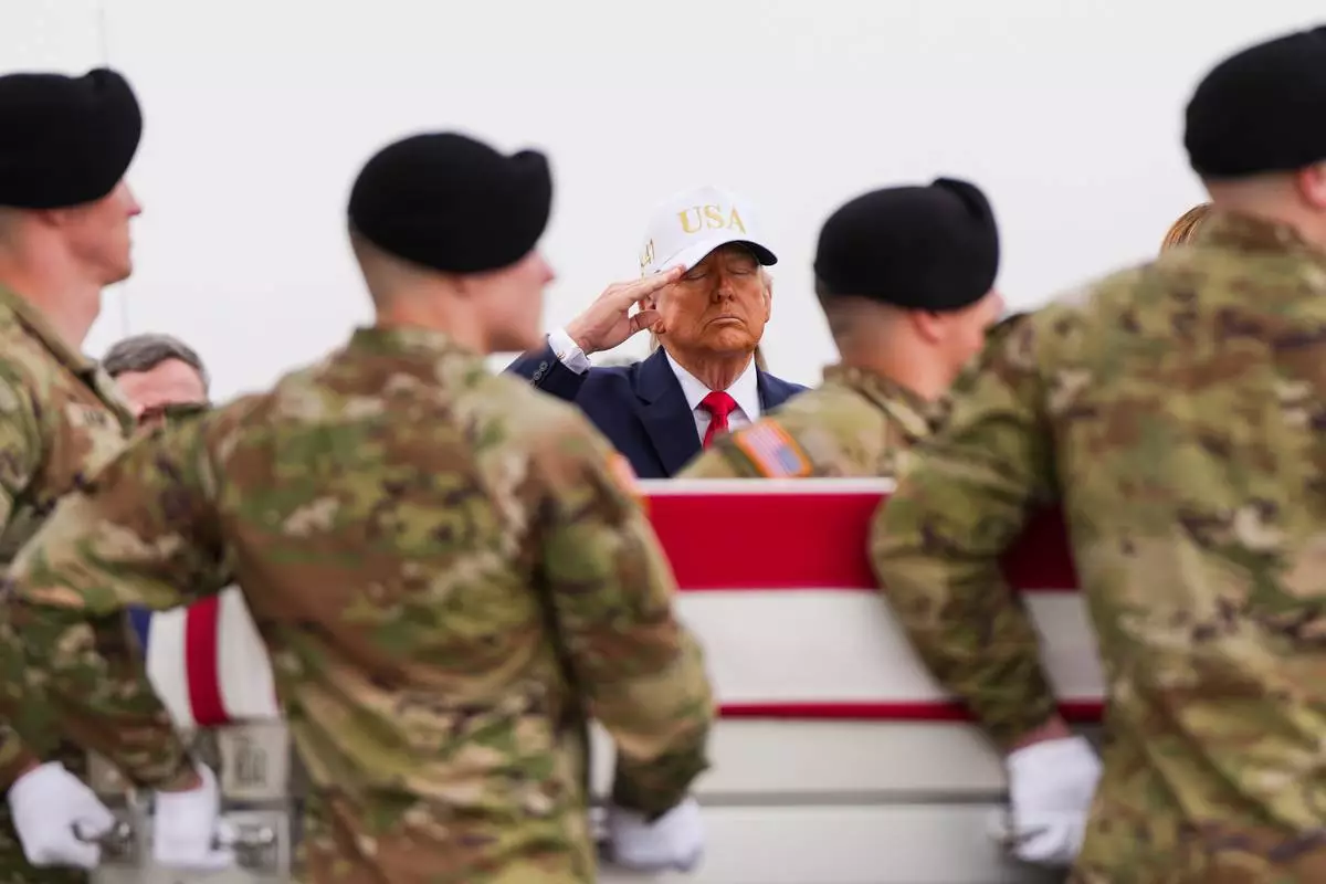 FILE - President Donald Trump salutes as an Army carry team moves a flag-draped transfer case with the remains of Sgt. Declan Coady, 20, of West Des Moines, Iowa, who was killed in a drone strike at a command center in Kuwait after the U.S. and Israel launched its military campaign against Iran, during a casualty return, March 7, 2026, at Dover Air Force Base, Del. (AP Photo/Julia Demaree Nikhinson, File)