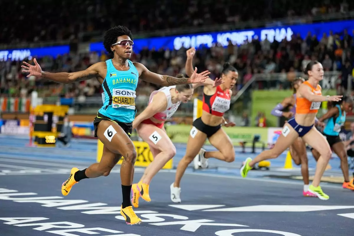 Devynne Charlton, of Bahamas, left, crosses the finish line to win the gold medal in the women's 60 meters hurdles final at the World Athletics Indoor Championships in Torun, Poland, Sunday, March 22, 2026. (AP Photo/Matthias Schrader)
