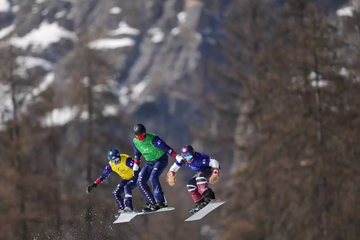 Zach Miller, of the United States, from left, Keith Gabel, of the United States, and Alex Massie, of Canada, compete in a men's snowboard cross SB-LL2 semifinal at the 2026 Winter Paralympics, in Cortina d'Ampezzo, Italy, Sunday, March 8, 2026. (AP Photo/Evgeniy Maloletka