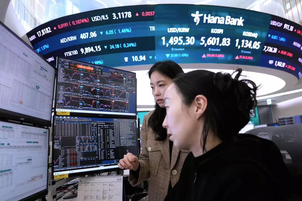 Currency traders watch monitors near a screen showing the Korea Composite Stock Price Index (KOSPI), top center, and the foreign exchange rate between U.S. dollar and South Korean won, top center left, at the foreign exchange dealing room of the Hana Bank headquarters in Seoul, South Korea, Tuesday, March 24, 2026. (AP Photo/Ahn Young-joon)