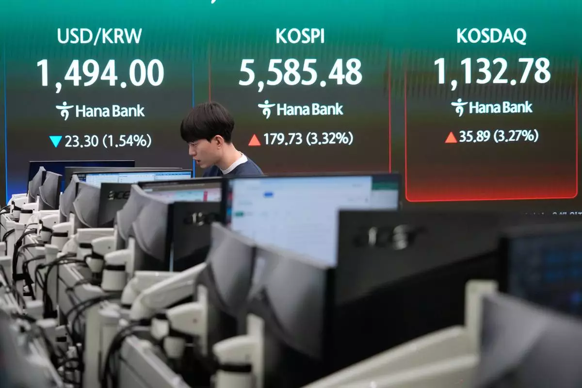 A currency trader watches monitors near a screen showing the Korea Composite Stock Price Index (KOSPI), top center, and the foreign exchange rate between U.S. dollar and South Korean won, top center left, at the foreign exchange dealing room of the Hana Bank headquarters in Seoul, South Korea, Tuesday, March 24, 2026. (AP Photo/Ahn Young-joon)