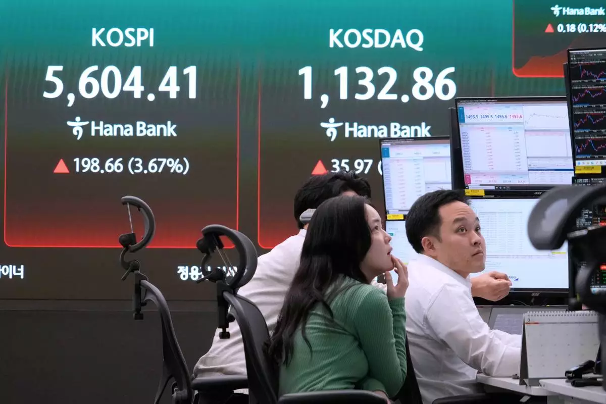 Currency traders watch monitors near a screen showing the Korea Composite Stock Price Index (KOSPI), left, at the foreign exchange dealing room of the Hana Bank headquarters in Seoul, South Korea, Tuesday, March 24, 2026. (AP Photo/Ahn Young-joon)