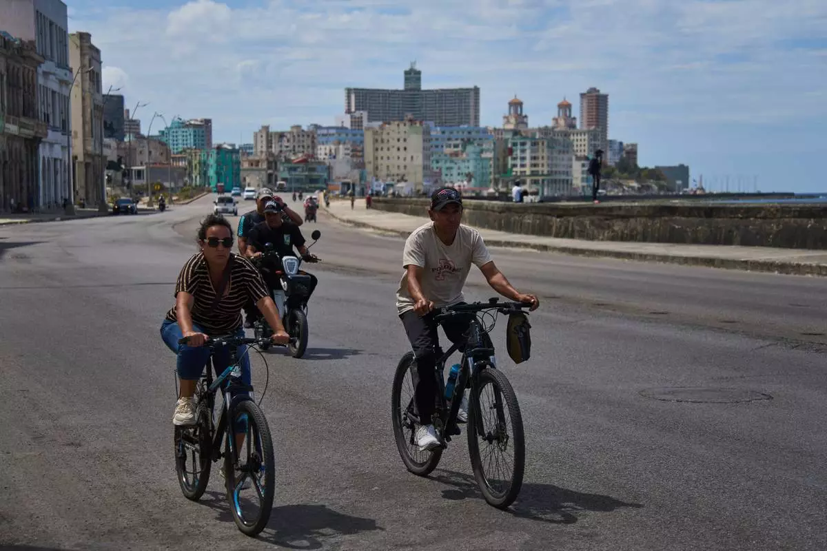 People ride their bicycles along the Malecón during a blackout in Havana, Cuba, Monday, March 16, 2026. (AP Photo/Ramon Espinosa)