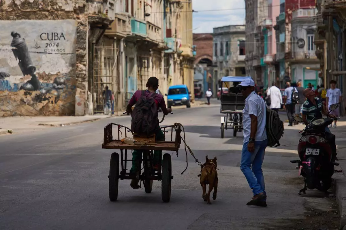 A man rides a tricycle with his leashed dog running alongside him during a blackout in Havana, Cuba, Monday, March 16, 2026. (AP Photo/Ramon Espinosa)